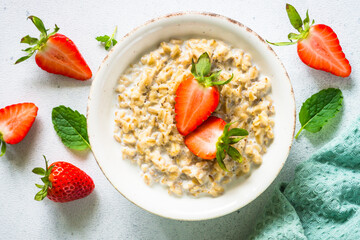 Wall Mural - Oatmeal porridge with strawberry on white background. Healthy breakfast. Top view.