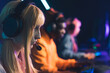 © PoppyPix - Group of online gamers, focus on the foreground. Beautiful blonde twenty-year-old gamer girl fighting in a tournament. High quality photo