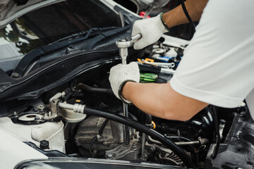 Wall Mural - Mechanic using a wrench and socket and repairing car engine in garage ,maintenance repair car concept ,selective focus