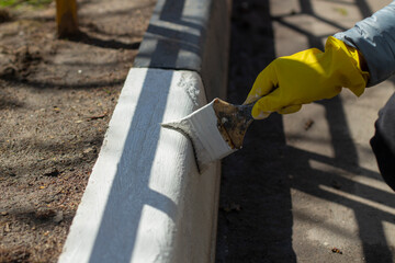 Paints the kerb with white paint. Brush with paint for the road curb.