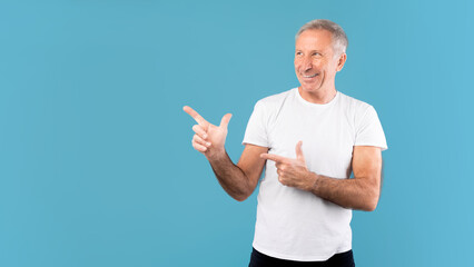 Wall Mural - Excited mature man pointing aside at copy space