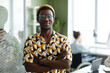 © Seventyfour - Waist up portrait of black young man wearing bright yellow pattern in office and looking at camera while posing confidently,copy space