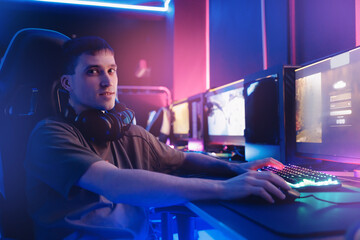 Wall Mural - Portrait Streamer young man professional gamer playing online games computer with headphones, neon color