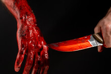 Man Holding Knife With Bloody Hand On Black Background. 