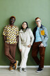 © Seventyfour - Minimal full length portrait of diverse creative team looking at camera while standing against green wall
