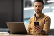 © Prostock-studio - Businessman Using Mobile Phone Sitting Near Laptop In Modern Office