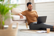 Arab Man Using Laptop Sitting On Floor At Home