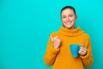 Young caucasian woman holding cup isolated on blue background pointing to the side to present a product