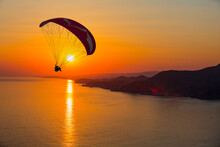 Paraglider Flies In The Sky At Sunset, Famous Cleopatra Beach In The Background - Alanya, Turkey