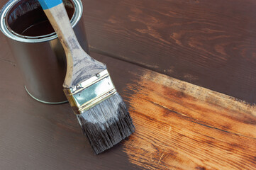 Paint brush and paint can on wooden surface