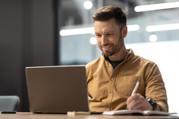 Canvas Print - Cheerful Entrepreneur Using Laptop And Taking Notes Working At Workplace