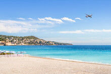 Beach And Plane. Flight To Vacation Destination By The Sea. Holiday Landscape. Airline Flying To Summer Paradise. Airplane On Blue Sky And Turquoise Water In Nice, France. Riviera Hotel Resort.