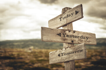 today yesterday tomorrow text quote written in wooden signpost outdoors in nature. moody theme feeli