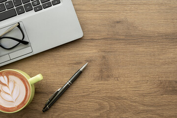 Wall Mural - Wood office desk table with laptop computer, cup of latte coffee and office supplies. Top view with copy space, flat lay.