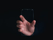 © tete_escape - Futuristic transparent glass phone Technology. Super slim transparent future smartphone with vertical mock-up blank screen in hand on dark background.