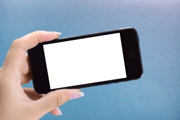 Poster - Hand holding phone with white screen on pastel background. Showing empty screen of modern cellphone.