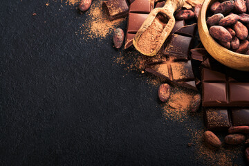 Wall Mural - Chocolate . Composition of cocoa powder, grated and bean cocoa bars and pieces of different milk and dark chocolate on black background. Baking Chocolate Texture. Top view with copy space. Mock up.