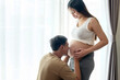 © tonefotografia - Young pregnant woman with husband embracing and expecting a baby at home