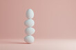 White eggs balance on a pastel pink background. 3D minimalistic design