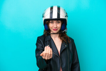 Wall Mural - Young caucasian woman with a motorcycle helmet isolated on blue background inviting to come with hand. Happy that you came