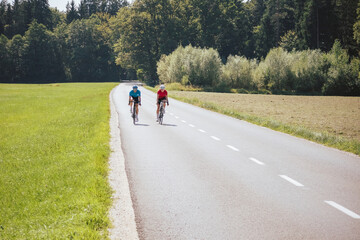 Wall Mural - Cyclists couple on the road in summer cycling gear pedaling and gliding positions on racing cycles.