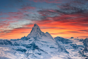 Wall Mural - Scenic view of snowcapped matterhorn mountain against cloudy sky. Beautiful famous snow covered landscape during sunset. Magnificent white valley in alps during winter.