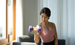 © Natee Meepian - Portrait of young asian woman lifting dumbbells at home