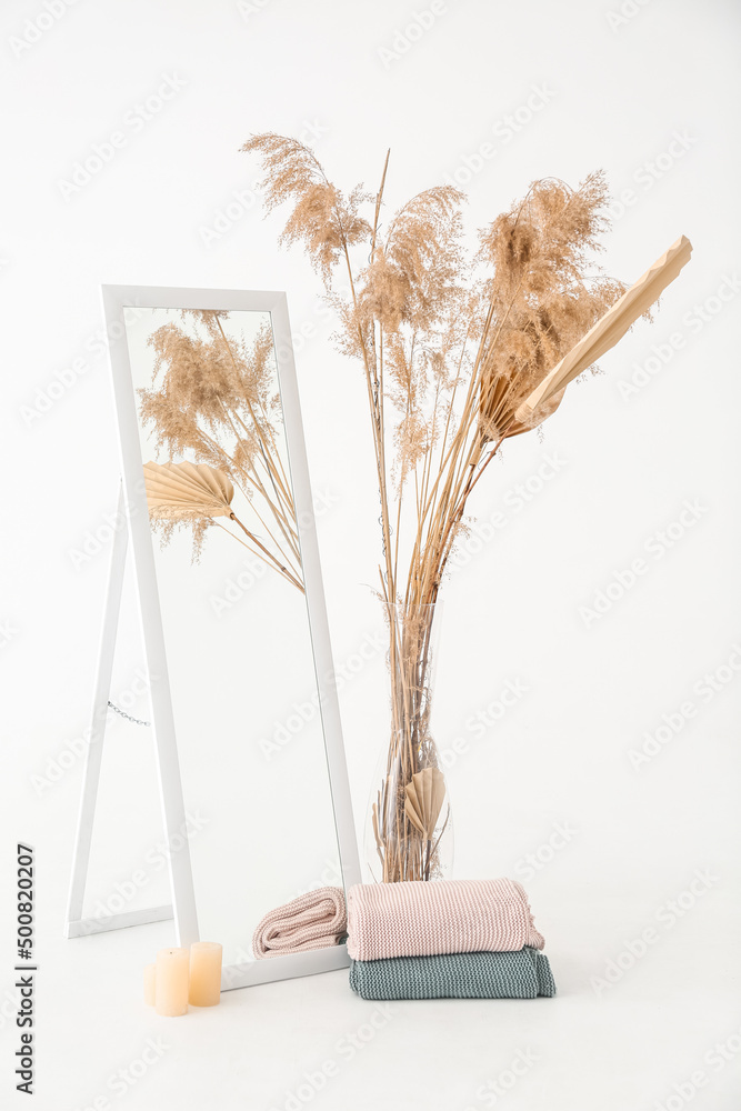 Warm plaids with mirror, candles and vase on white background