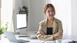 © Prathankarnpap - Pretty female employee sitting in modern office and smiling confidently to camera.