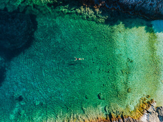 Wall Mural - overhead view of woman floating on back in clear sea water