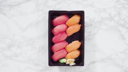 Canvas Print - Flat lay. Pre-packaged variety of sushi and sushi rolls in a plastic tray.