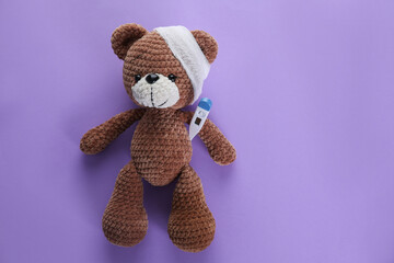 Wall Mural - Toy bear with bandage and thermometer on violet background, top view with space for text. Children's hospital