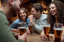 Group Of Happy Friends Having Beer And Socializing In A Pub