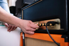 Hands Of Man Using Amplifier In Home Studio