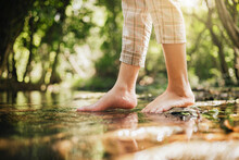 Woman Wading Barefoot In Stream In Nature Forest