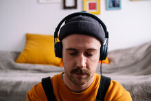 Man With Eyes Closed Listening Music Through Headphones At Home