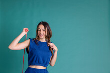 Smiling Young Woman With Jumping Rope Against Blue Background