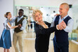 © caftor - Elderly woman learning ballroom dancing movements in pair