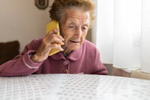 Senior Woman With Brown Hair Talking On Mobile Phone Sitting At Dining Table
