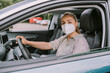 © Westend61 - Young woman with protective face mask driving car