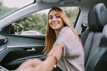 Happy Blond Woman Holding Hand Sitting On Front Passenger Seat In Car