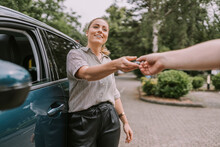 Smiling Woman Giving Car Key To Man At Parking Lot