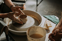 Hands Of Craftsperson Molding Bowl On Potter's Wheel In Workshop