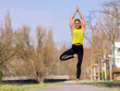 © Westend61 - Smiling woman practicing tree pose on footpath