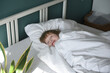 © Westend61 - Smiling boy with blanket sleeping in bed at home
