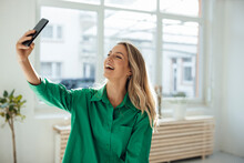 Happy Woman Taking Selfie Through Mobile Phone At Home