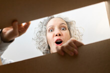 Surprised Woman Opening Cardboard Box At Home