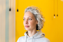 Woman With Gray Hair Standing In Front Of Yellow Wall