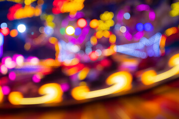 Wall Mural - Unfocused lights of a Merry-go-round or carousel with colorful blue, red, yellow, pink and orange illumination. Blurred lights traces and spots taken with Long Time Exposure on a fun fair in Germany. 