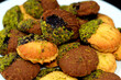 Traditional Arabic cookies for celebration of Islamic holidays of El-Fitr feast, petit four bakery (mignardises) stuffed with jam and nuts and covered with chocolate and pistachios on a white plate